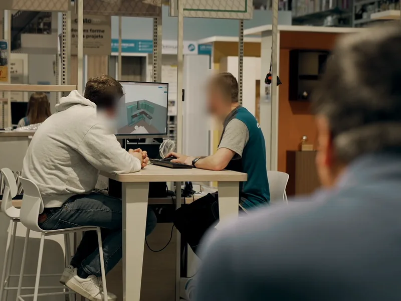 En magasin, Stéphane Thanasack observe un vendeur et un client qui conçoivent un projet sur écran.